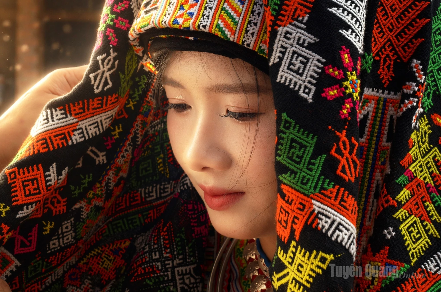 Bride Ngoc Dung shyly poses beneath an intricately embroidered, brightly colored headscarf.