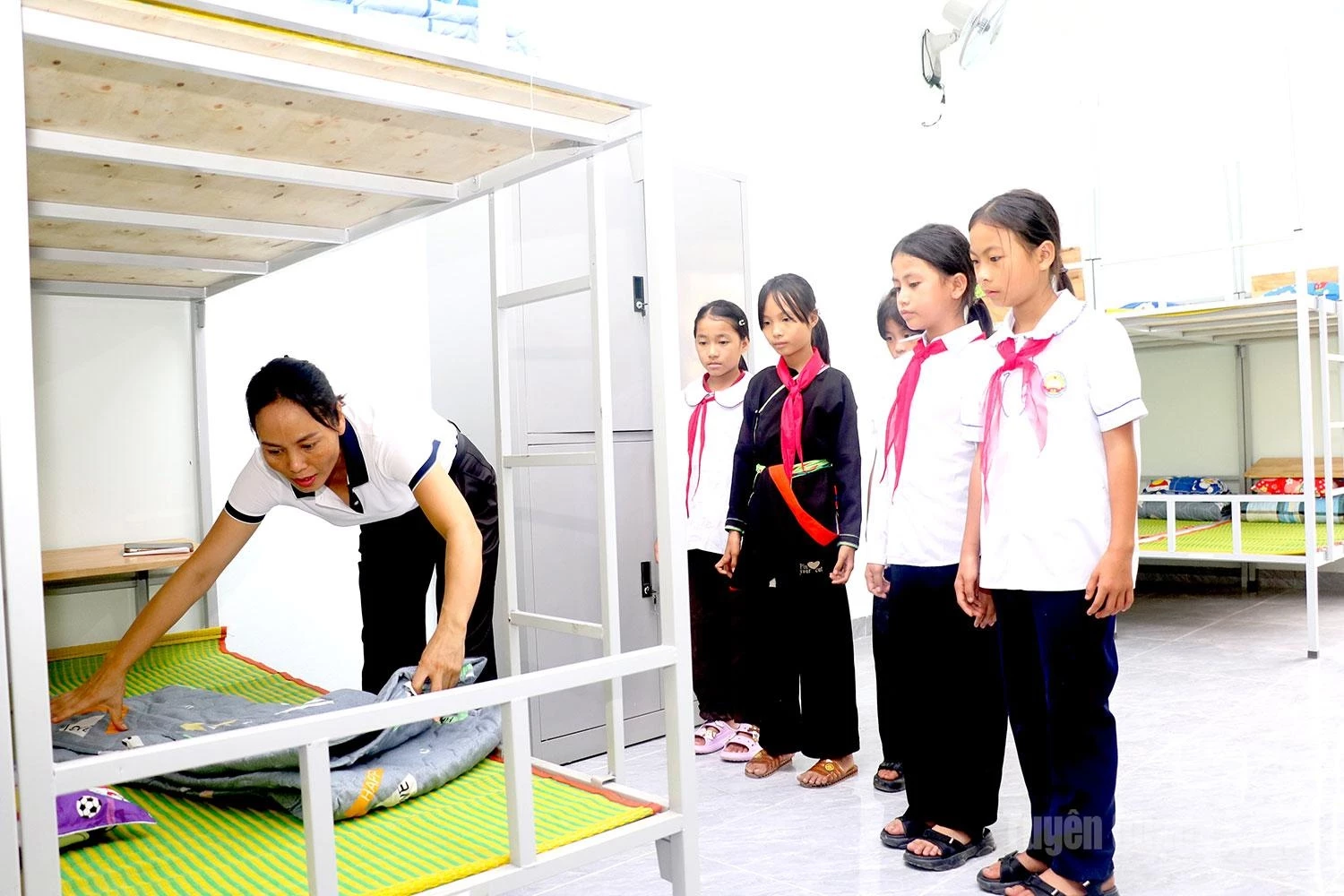 A teacher patiently guides students in folding their blankets and arranging their belongings – small daily tasks that help them gradually develop independence and maturity.
