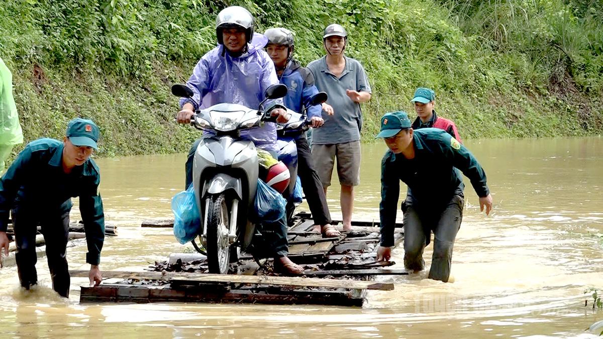 Lực lượng dân quân tự vệ xã Bắc Quang hỗ trợ người dân thôn Lung Cu, xã Bắc Quang di chuyển qua đoạn ngập lụt trên Quốc lộ 279. Ảnh Thanh Loan - TTVH khu vực Bắc Quang