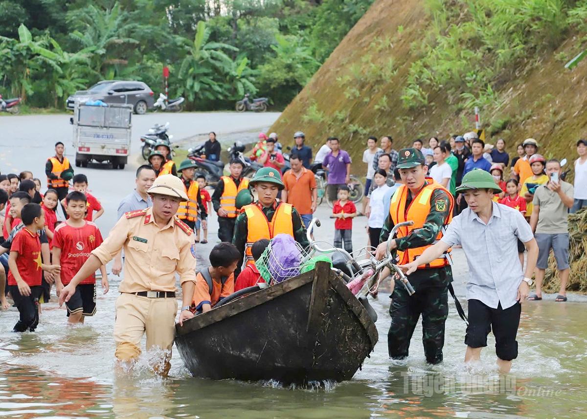 Cán bộ, chiến sỹ Ban Chỉ huy PTKV 3 - Bắc Quang cùng lực lượng Cảnh sát giao thông đưa người dân qua khu vực đường ngập úng.
