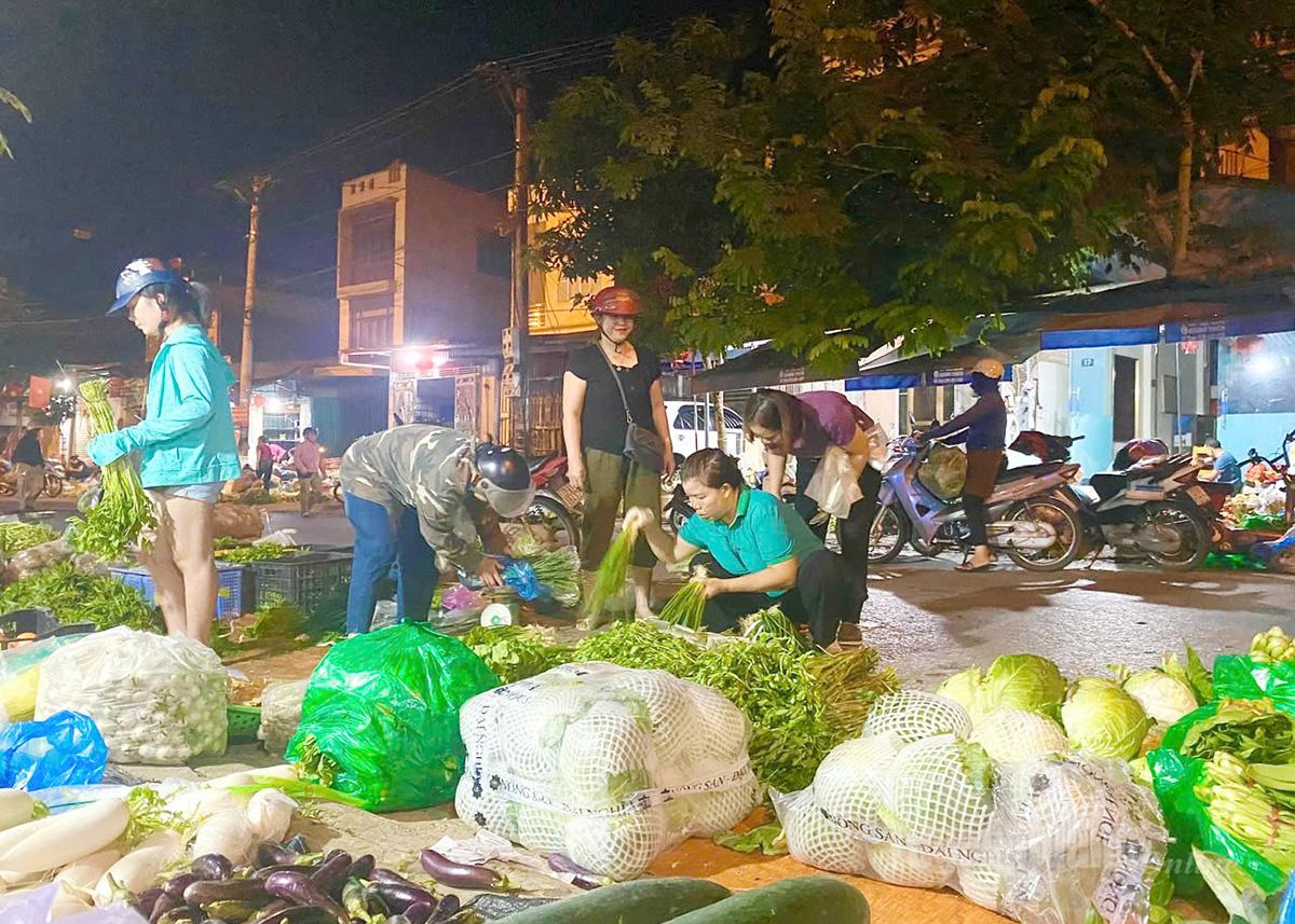 In the shimmering light, the vegetable and fruit traders create a vivid picture of labor.