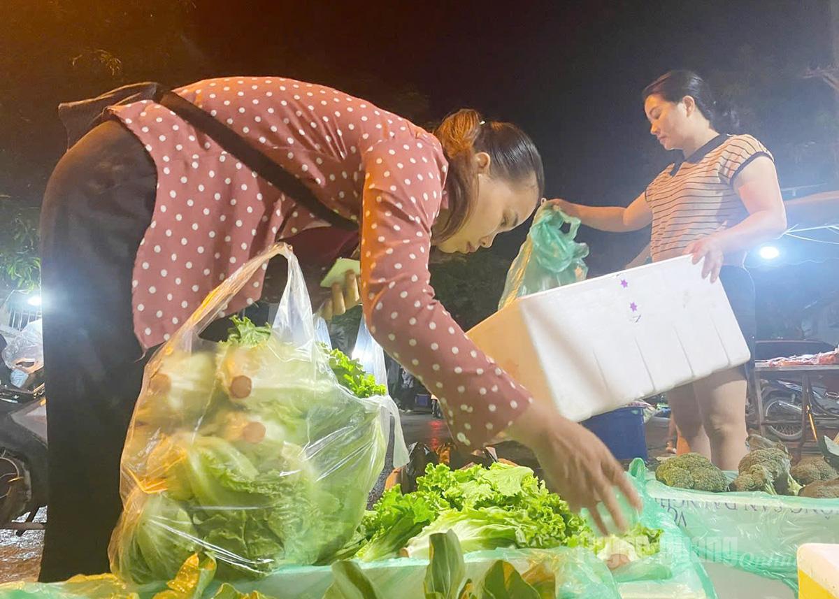 Buyers carefully select each fresh green bunch of vegetables.