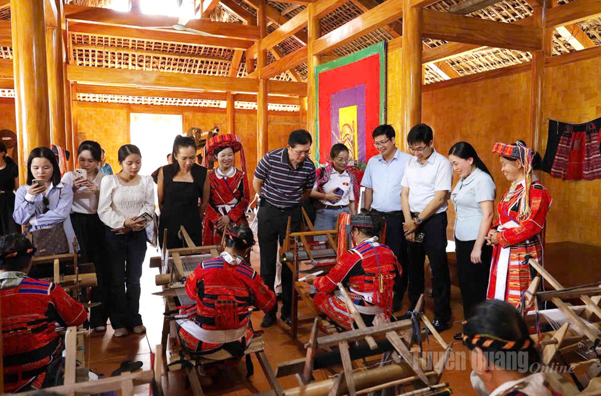 Du khách trải nghiệm không gian văn hóa Pà Thẻn tại nhà sinh hoạt cộng đồng, nơi những khung cửi luôn đỏ sợi chỉ thổ cẩm.