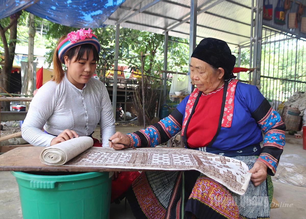 Phụ nữ Mông tỉ mỉ vẽ sáp ong lên vải lanh để tạo hoa văn truyền thống trước khi nhuộm chàm.