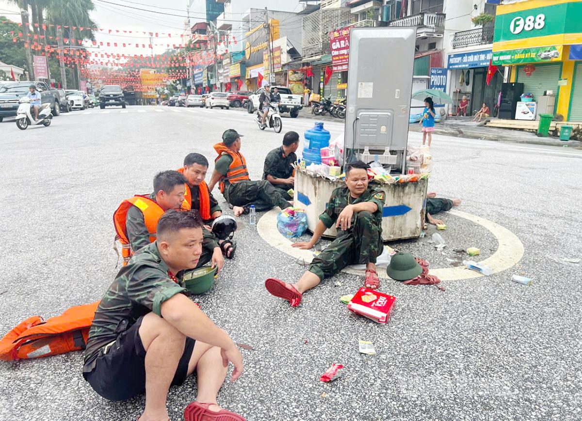 Phút nghỉ ngơi của cán bộ, chiến sĩ Trung đoàn 877 sau khi dầm mình trong nước giúp bà con nhân dân. Ảnh Tạ Hương