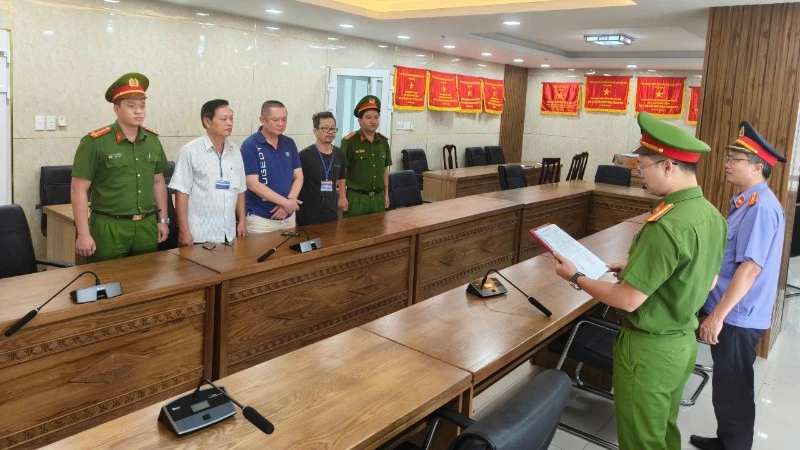 Cơ quan điều tra tống đạt các quyết định khởi tố đối với ba bị can. (Ảnh: Công an cung cấp)