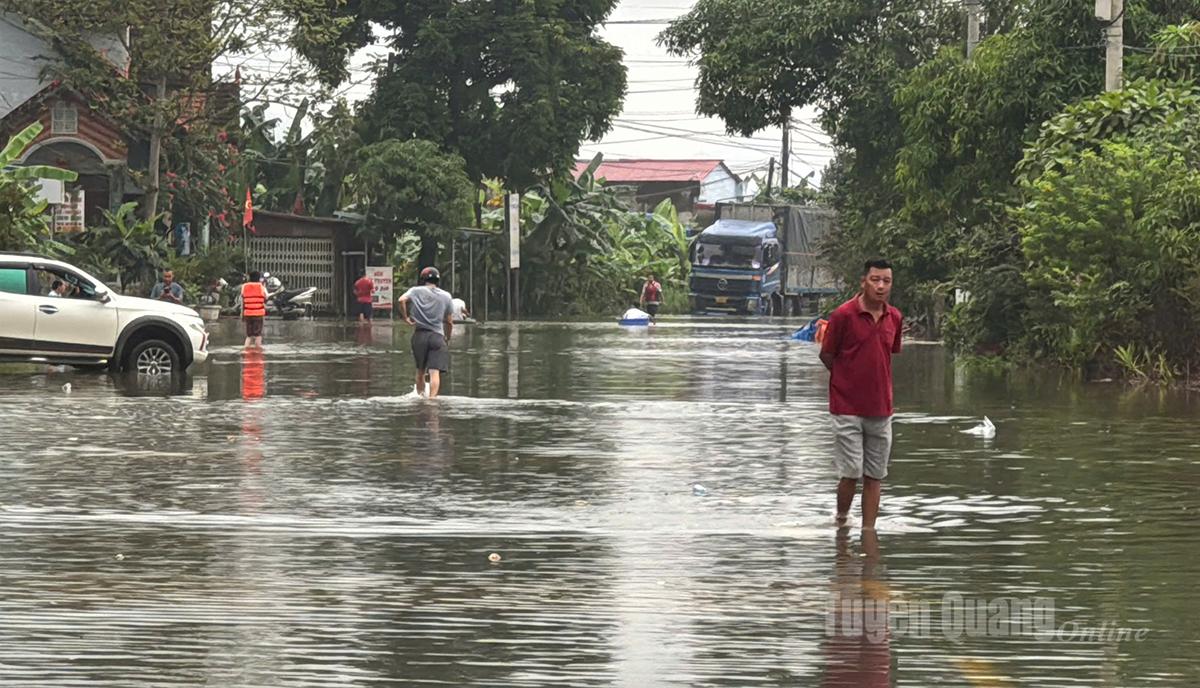 6h15. Đoạn QL2, Km48 thuộc xã Tân Quang, nước lũ đã bắt đầu dâng cao, nhiều phương tiện và người dân phải di chuyển khó khăn. Ảnh: Mai Ánh
