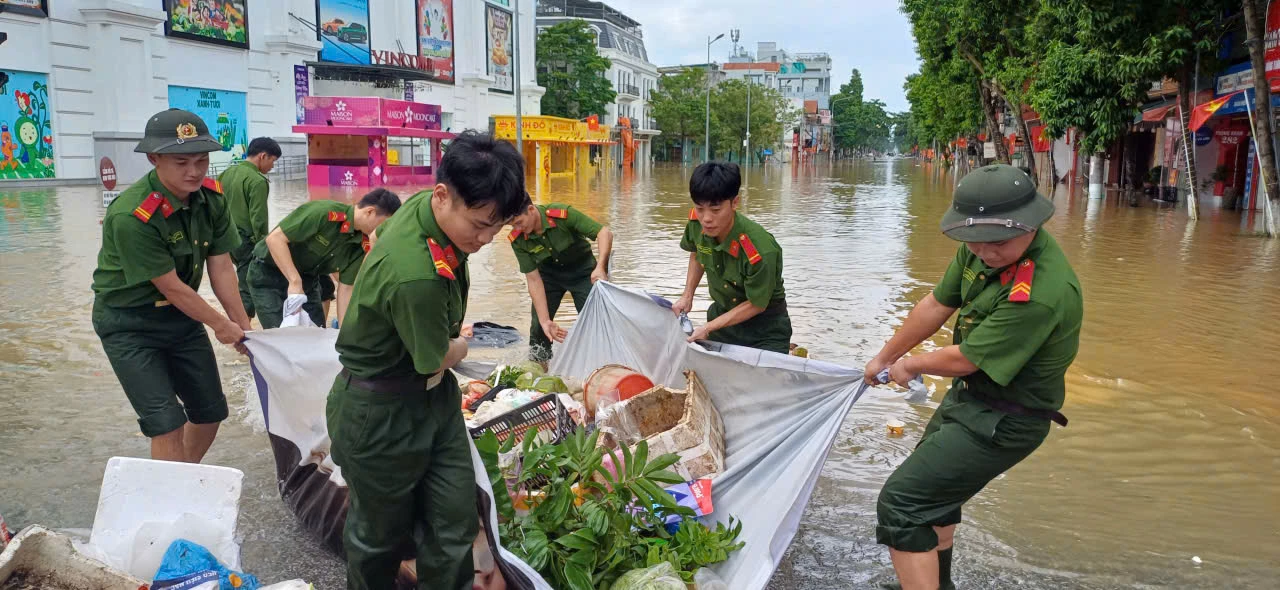 Gần 12h trưa, lực lượng Công an tỉnh vẫn tích cực vệ sinh môi trường tại điểm ngập sâu đường Quang Trung, phường Minh Xuân. Ảnh: Mộc Lan