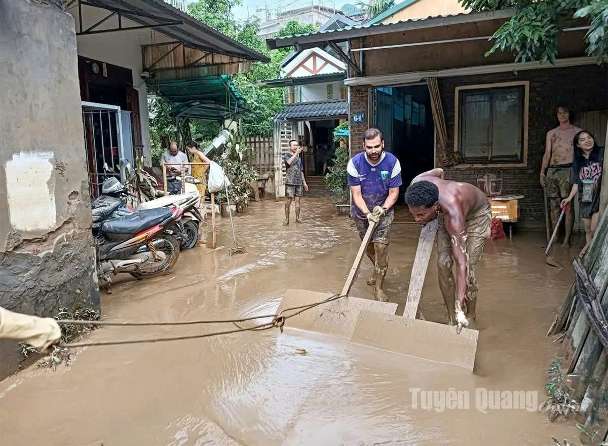 Khách du lịch tham gia hỗ trợ người dân phường Hà Giang 2 dọn dẹp bùn đất sau lũ. Ảnh: Mộc Lan