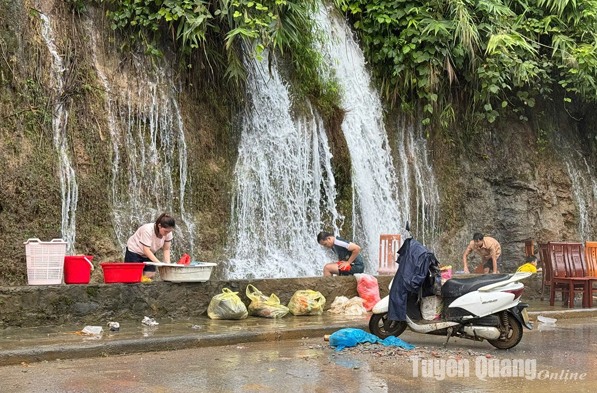 Tình trạng mất nước sau lũ khiến người dân phải mang đồ đạc ra khu vực con đường thác nước, phường Hà Giang 2, để làm sạch. Ảnh: Minh Châu