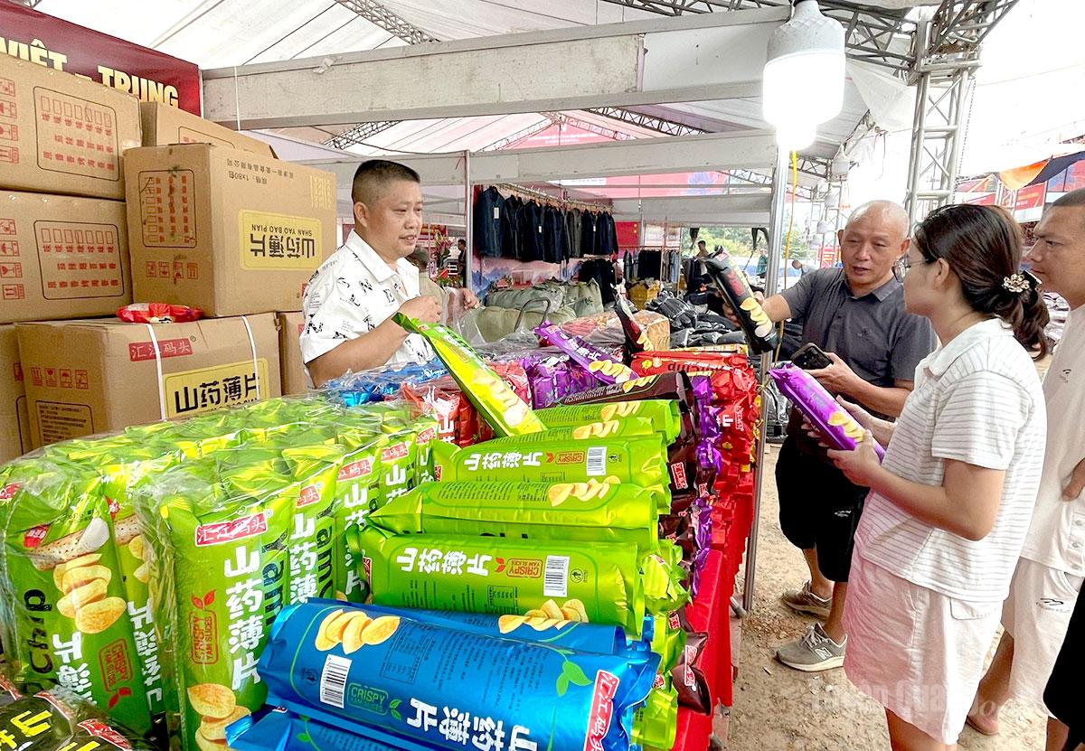 Tiểu thương Trung Quốc giới thiệu các loại bánh snack, khoai tây chiên giòn đóng gói cho khách tham quan.