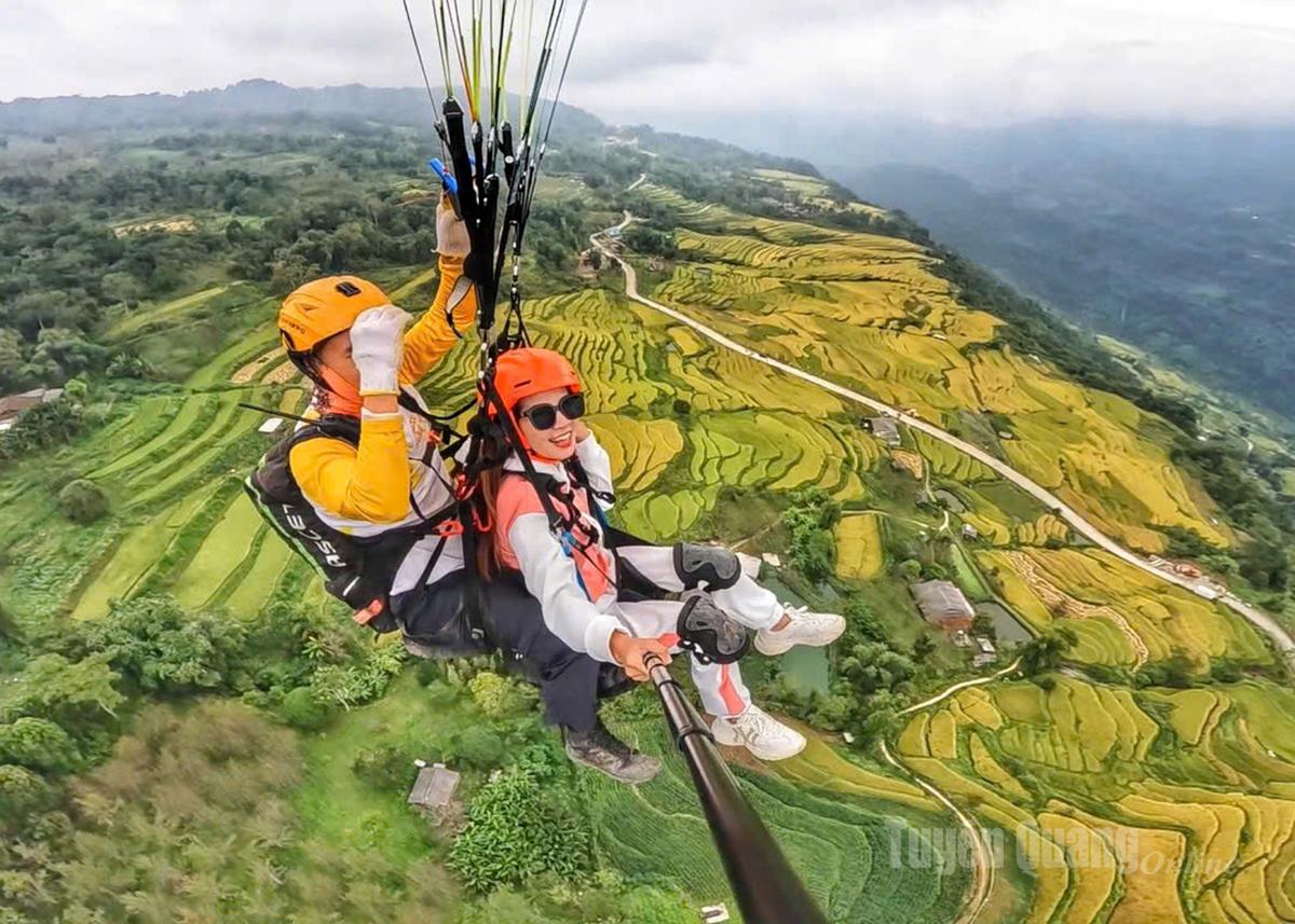 Tourists experience paragliding over the golden season in Hong Thai commune.
