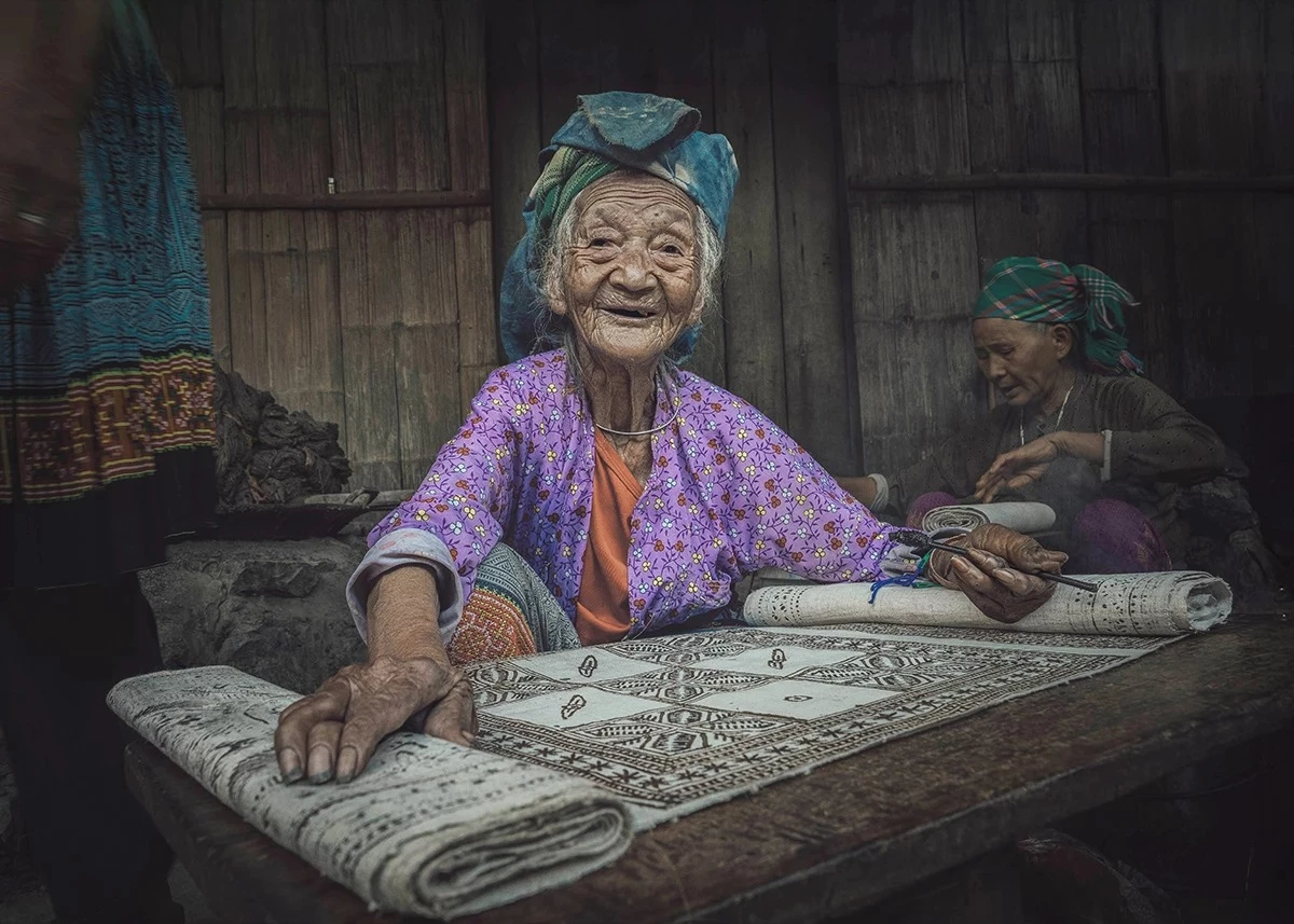 Although her hands are deformed, Mrs. Sung Thi Co from Hop Tien village, Lung Tam commune, tirelessly pursues the craft of beeswax painting on linen.