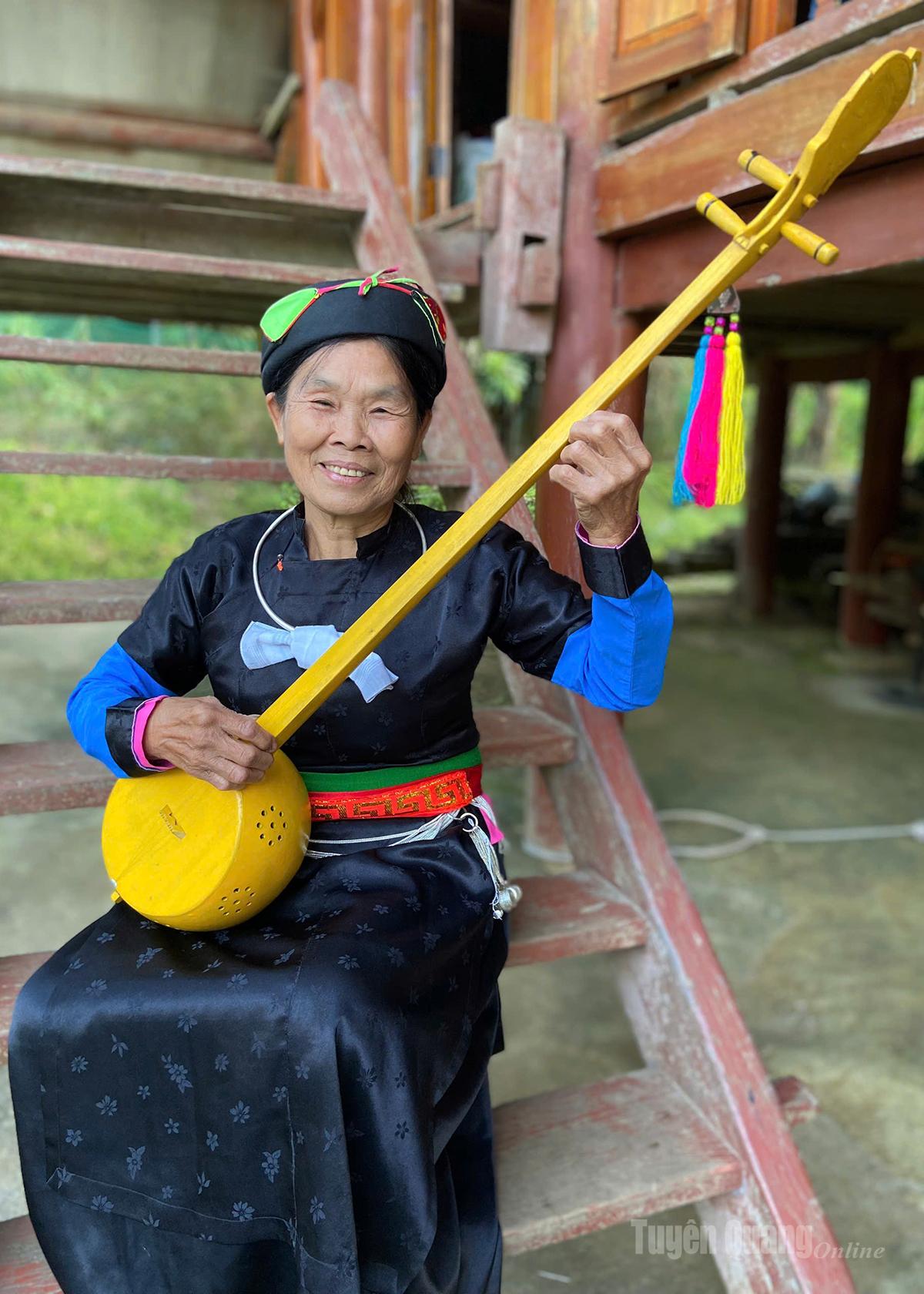 Bà Ma Thị Nghiêu, Chủ nhiệm CLB hát Then thôn Nặm Lương, xã Phù Lưu bên cây đàn Tính.