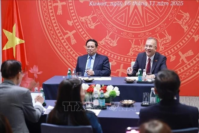 Prime Minister Pham Minh Chinh (left) meets with staff of Vietnamese representative offices and the Vietnamese community in Kuwait on the evening of November 16. (Photo: VNA)