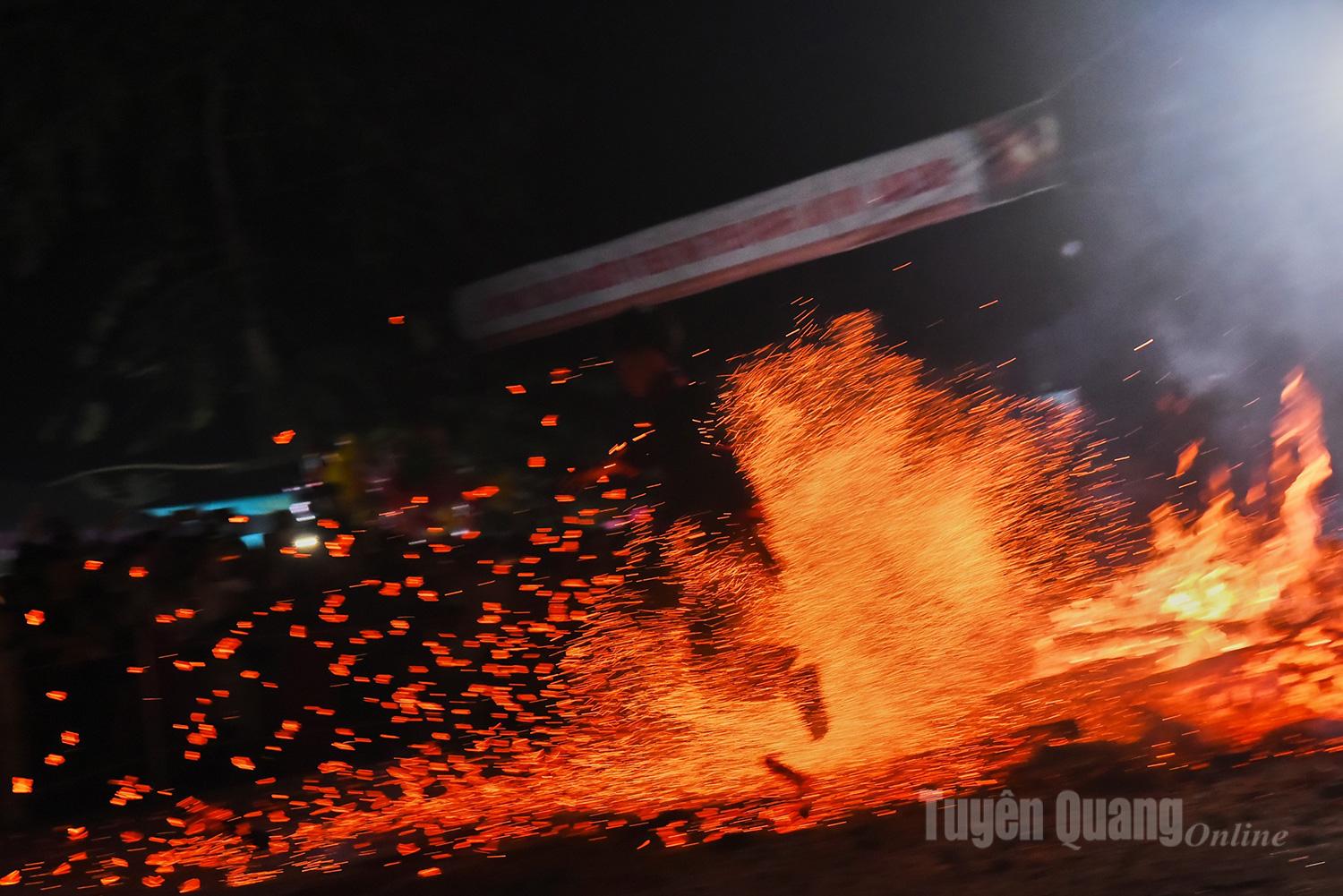 Continuous leaps on the burning coals send embers flying, forming streams of light within the circle of spectators.