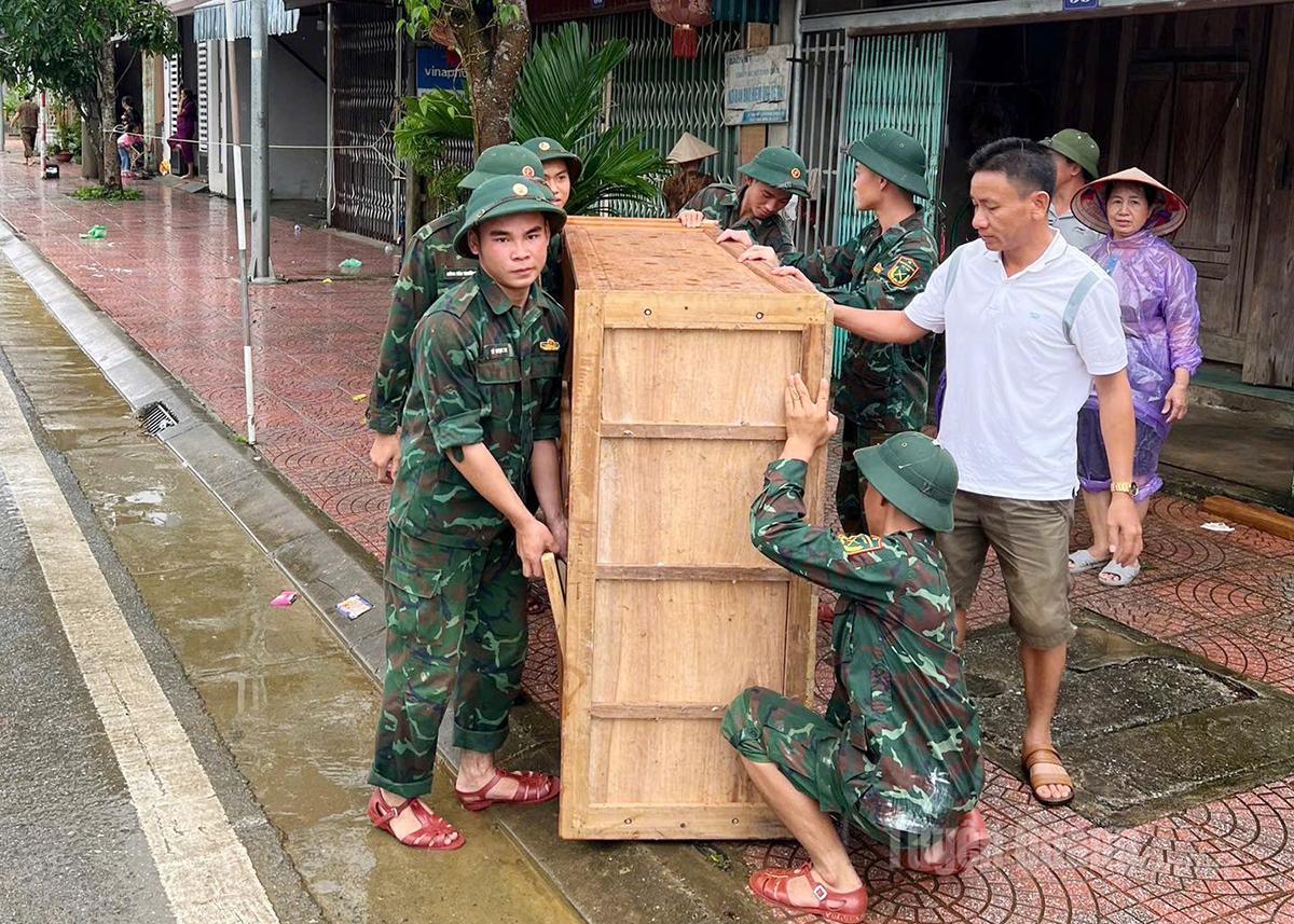 Officers and soldiers help local people transport belongings after flooding in Na Hang Commune.