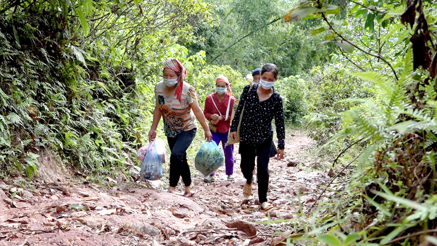 Người dân đi bộ tới trung tâm xã mua thực phẩm. 