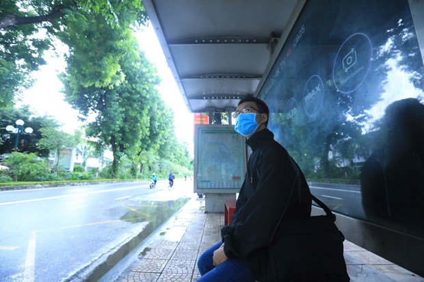 Người dân chờ xe buýt tại trạm đón, trả khách trên phố Giảng Võ, Hà Nội. 