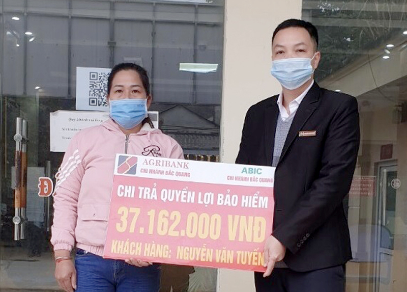 Ông Nguyễn Cung Trăng - Phó Giám đốc Phòng giao dịch Kim Ngọc trao biểu trưng chi trả quyền lợi Bảo an tín dụng cho đại diện gia đình Ông Nguyễn Văn Tuyến